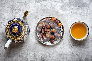 Popular food during Iftar - dry dates, teapot, bowl with black tea on concrete background Top view Flat lay Muslim holiday of holy