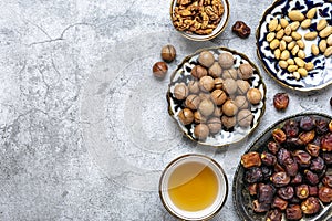 Popular food during Iftar - macadamia nuts, pistachios, walnuts, dry dates. Karan, rosary, teapot, bowl with black tea on concrete