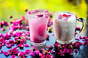 Popular Indian & Asian Summer drink on wooden surface i.e. Gulab falooda or gulab ka sherbat with some rose petals on black
