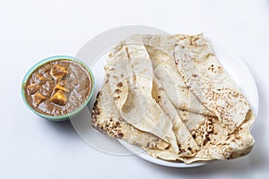 Popular Indian food on white background served with butter masala curry in a bowl with delicious butter naan on white plate