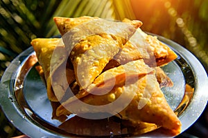 Popular Indian street food. Vegetarian samosa with potatoes, onions, beans and masala. Triangular pie, fried in oil, close-up