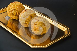 Popular Indian sweet dish known as Boondi laddu served in golden platter. photo