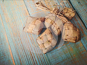 Popular Malay traditional Ramadan food Ketupat rice or Ketupat Palas with selective focus on wooden background.