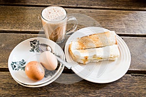 Popular Malaysian breakfast teh tarik, toast bread and half-boiled egg photo