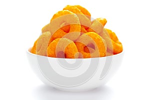 Popular Ready to eat crunchy and puffed snacks ring tangy orange color in a white ceramic bowl. Top view,