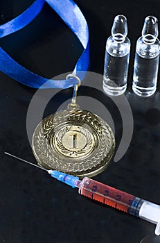 Popular red steroid in syringe and ampoules as a doping near a gold medal on a dark background