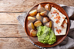 Popular Scandinavian food Lutefisk from cod with pea puree, baked potatoes and bacon close-up on a plate. Horizontal top view photo