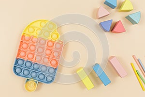 Popular silicone pastel anti-stress pop it toys and wooden cubes for a child on beige background. Trendy Sensory Fidget Toy.