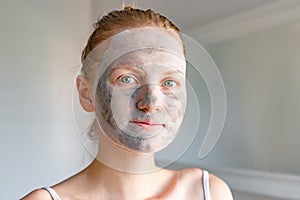 Popular spa treatment bubbling mask with charcoal oxygen purifying product on the face of beautiful girl with green eyes