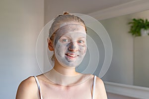 Popular spa treatment bubbling mask with charcoal oxygen purifying product on the face of beautiful girl with green eyes