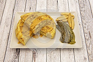 Popular Spanish potato omelette accompanied by roasted peppers, peaks and cheese sauce on a white tray photo