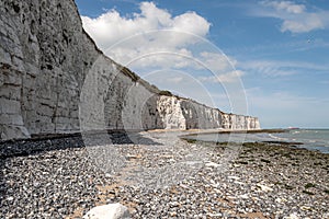 Popular tourist attraction and relax by the ocean concept with wide chalk wall made of white cliffs on warm summer day and waves