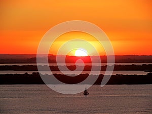 Por do sol com cÃÂ©u amarelo e barco veleiro na ÃÂ¡gua photo