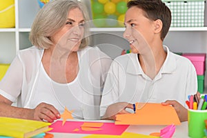 Porait of grandmother teaches her grandson to do craft items