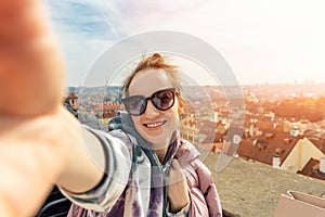 Poratrait of young adult happy woman taking photo selfie at travel trip in prague with rooftop old town panoramic