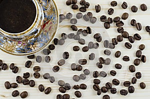 Porcelain coffee cup and coffee beans on wooden table