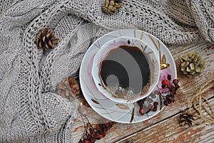 Porcelain cup of black coffee on the rustic background with winter decoration. Square format of photo