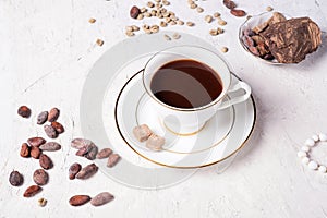 Porcelain cup of mocca coffee with natural chocolate, cocao beans, green coffe beans and neck beads around white provence