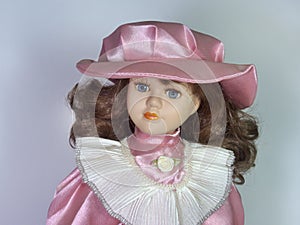 A porcelain doll with big beautiful eyes. In an elegant hat with