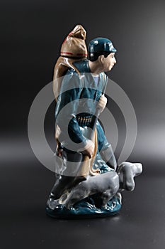 Porcelain figure of the hunter with a dog against a dark background, subject shooting.