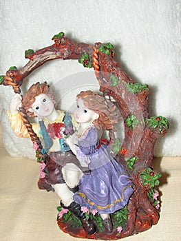 Porcelain figures on a swing- summer