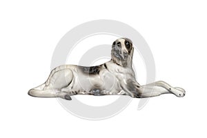 Porcelain figurine in the shape of a dog lying on the ground with folded paws, isolated on a white background with a clipping path