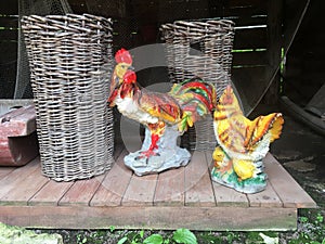Porcelain figurines of roosters standing on the street near the wicker baskets