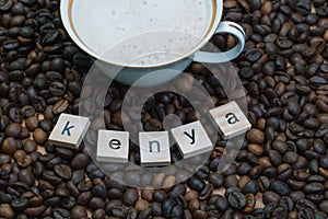Porcelain and gilded cup of coffee on a background of coffee beans with the inscription Kenya. Production, export and photo