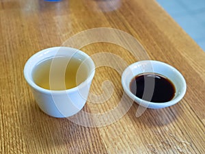Porcelain glass of tea and small bowl of soy sauce on Asian restaurant table