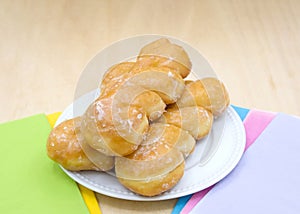 porcelain plate with glazed and frosted cake donuts with sprinkles on a light wood table