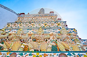 Porcelain sculptures of Yakshas - the spirit guardians, on the wall of Wat Arun temple in Bangkok, Thailand