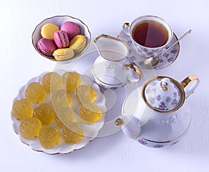 Porcelain tea set with milk, macaroni and marmalade, milk jug, tea cup, cup and saucer, gummy candy