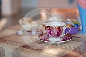 Porcelain vintage cup with saucer for tea stands on a table covered with a spiky tablecloth.