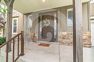 Porch and front door of a home with wood and stone brick wall sections