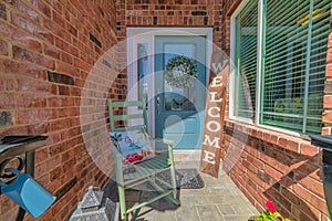Porch of home with rocking chairs and welcome signboard against blue front door