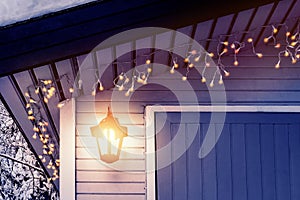 Porch of the house is decorated in the traditional Scandinavian style with a lantern and Christmas lights - concept of home warmth