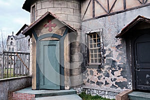 Porch of an old Catholic Church with a door, a cross and a canopy over the closed entrance