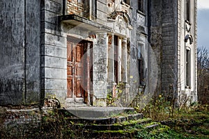 Porch of an old palace with a stone staircase and a red door