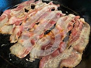 Pork Bacon Cooking in Cast Iron Skillet