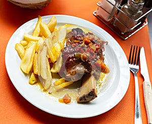 Pork baked shank with vegetables and french fries served