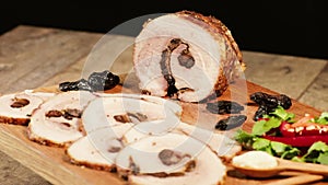 Pork belly baked in the oven with spices and prunes. Sliced meat on a wooden board