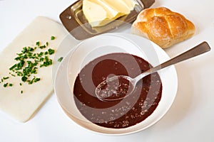Pork blood soup with groats, butter, bun and chive on white
