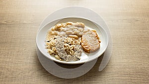 Pork chop, Brown rice and white beans. White dish on wooden table.