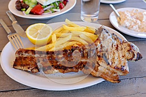 Pork chop with french fries portion in greek tavern.