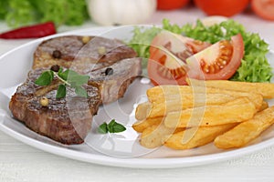 Pork chop steak meat meal with fries, vegetables and lettuce on