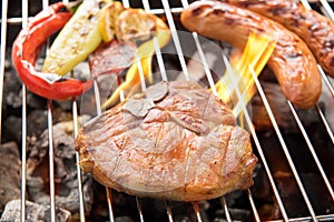 Pork chop steak and vegetable with sausage on a flaming BBQ grill