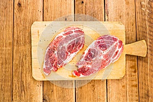 Pork chops with condiments on a wooden cutting board over wooden table, meat for bbq, top view, copy space, barbeque concept