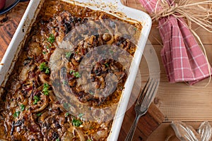 Pork cutlets in a creamy onion bacon sauce in a baking dish on wooden table