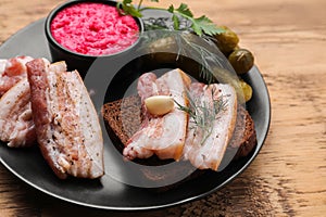 Pork fatback with rye bread and ingredients on wooden table, closeup