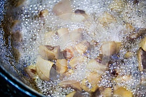 Pork greaves scraps boiling in grease in big metal pot